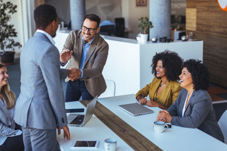Professional Team Welcoming New Colleague During Business Meeting Discussion