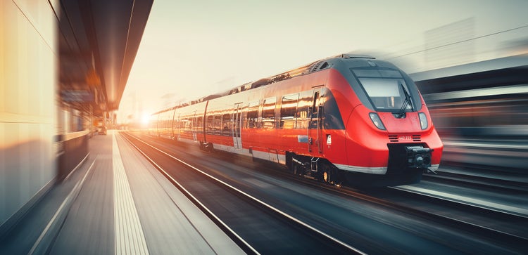 Beautiful railway station with modern high speed red commuter train with motion blur effect at colorful sunset in Nuremberg, Germany. Railroad with vintage toning