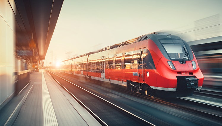 Beautiful railway station with modern high speed red commuter train with motion blur effect at colorful sunset in Nuremberg, Germany. Railroad with vintage toning